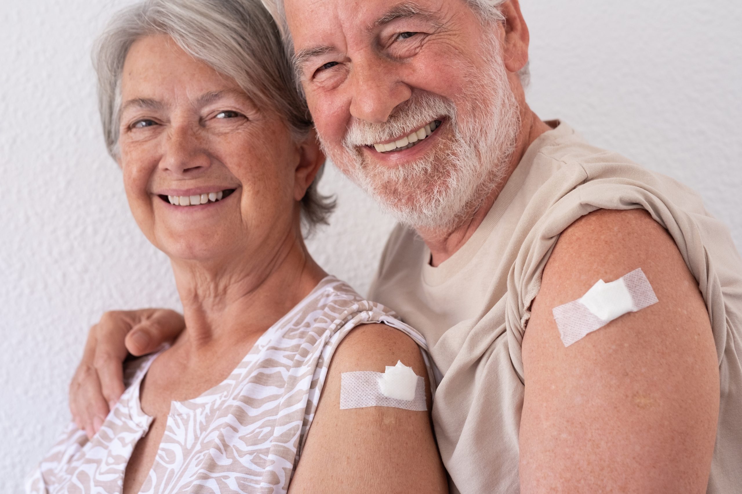 smiling senior couple with bare arms and bandages